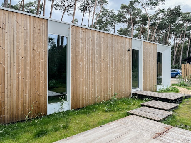 Prefab houtskeletbouw vakantiewoning prototype #80A van Skilpod. Afwerking in natuurhout en witte ramen.