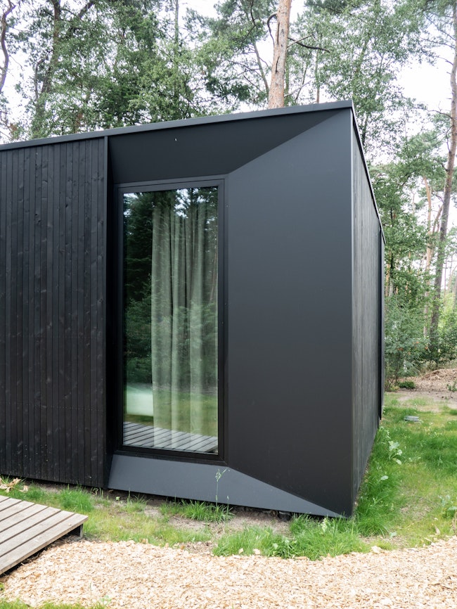 Prefab houtskeletbouw vakantiewoning prototype #80A van Skilpod. Afwerking in zwart hout en zwarte ramen.